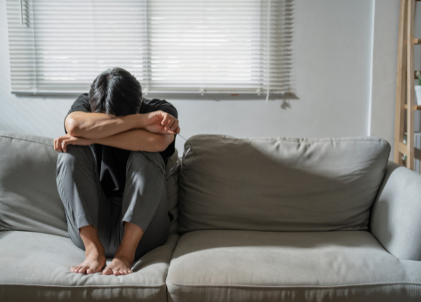 A person sitting on a couch with their head in their hands.