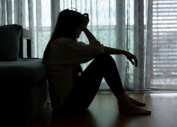 A person sitting on the floor in front of a window