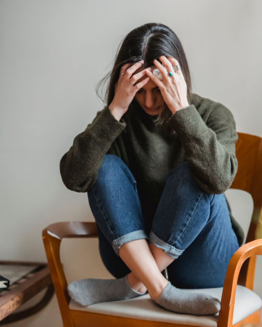A person sitting on a chair with their hands on their head