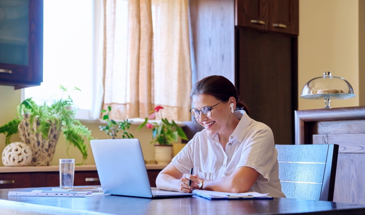 therapist sitting at desk looking at computer screen smiling